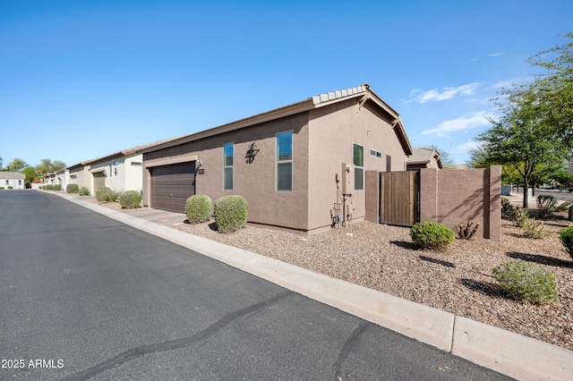 view of property exterior with a garage, stucco siding, and a gate