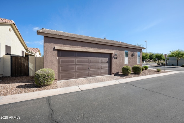view of front of property with driveway, stucco siding, a gate, and an attached garage