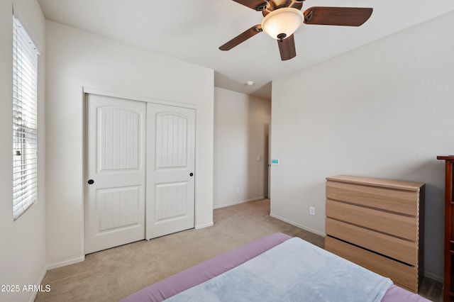 bedroom with carpet flooring, a closet, baseboards, and a ceiling fan