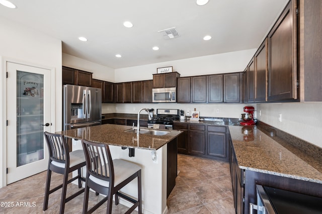kitchen featuring a sink, dark brown cabinets, appliances with stainless steel finishes, and dark stone countertops
