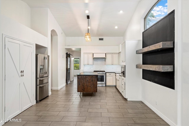 26264 N 46th St, Phoenix, AZ 85050 - kitchen featuring appliances with stainless steel finishes, a kitchen island, backsplash, vaulted ceiling, and hanging light fixtures
