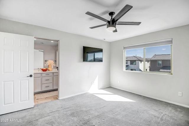 unfurnished bedroom featuring light colored carpet, ceiling fan, baseboards, and ensuite bathroom