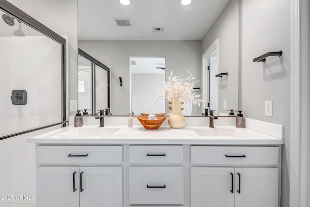 full bath with double vanity, a stall shower, visible vents, and a sink