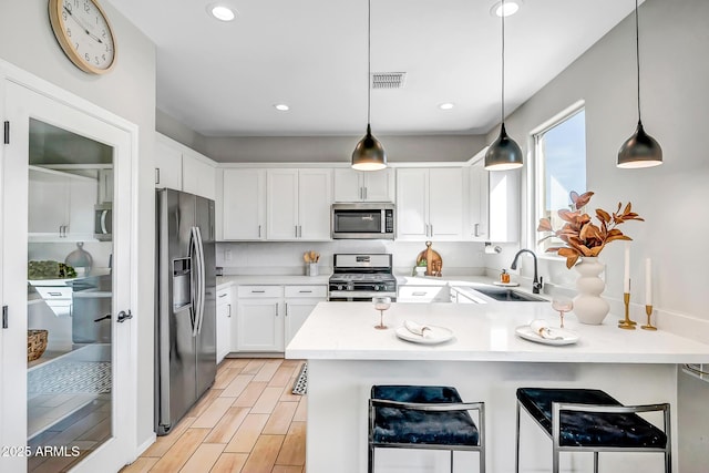 kitchen featuring visible vents, appliances with stainless steel finishes, a peninsula, light countertops, and a sink