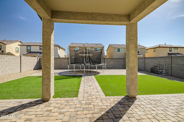 view of yard featuring a trampoline, a patio area, and a fenced backyard