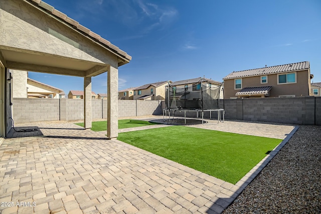 exterior space with a patio, a trampoline, a fenced backyard, and a residential view