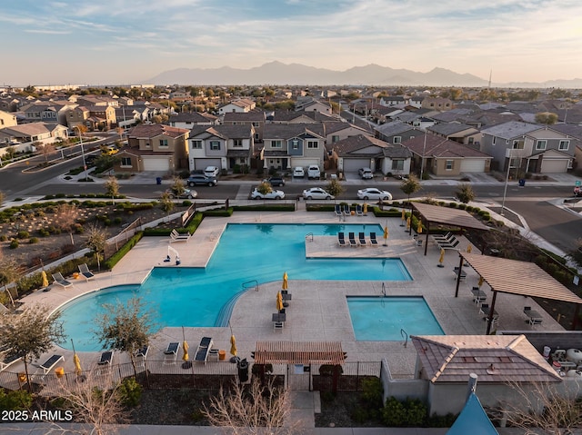 pool featuring a residential view, a mountain view, a patio, and fence