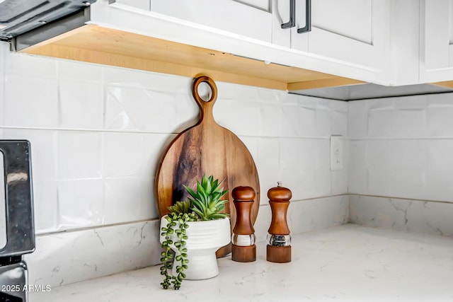 interior details featuring white cabinets and light stone countertops