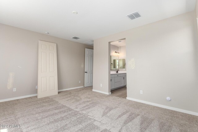 unfurnished bedroom with light colored carpet and ensuite bathroom