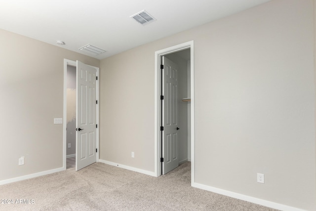 unfurnished bedroom with light colored carpet and a spacious closet