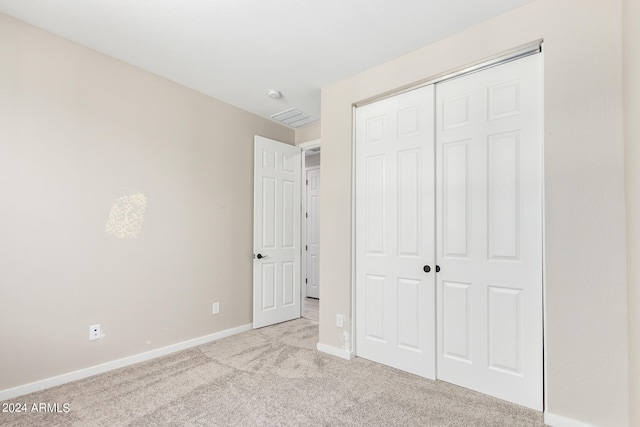 unfurnished bedroom with a closet and light colored carpet