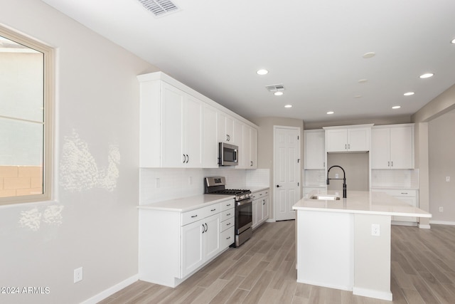 kitchen featuring white cabinets, sink, a kitchen island with sink, appliances with stainless steel finishes, and light hardwood / wood-style floors