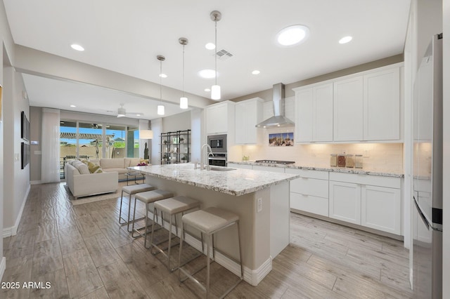 18746 W Rancho Dr, Litchfield Park, AZ 85340 - kitchen with appliances with stainless steel finishes, open floor plan, white cabinets, and wall chimney exhaust hood