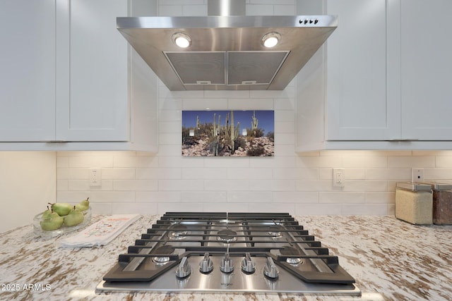 18746 W Rancho Dr, Litchfield Park, AZ 85340 - room details with light stone countertops, stainless steel gas stovetop, wall chimney range hood, and decorative backsplash