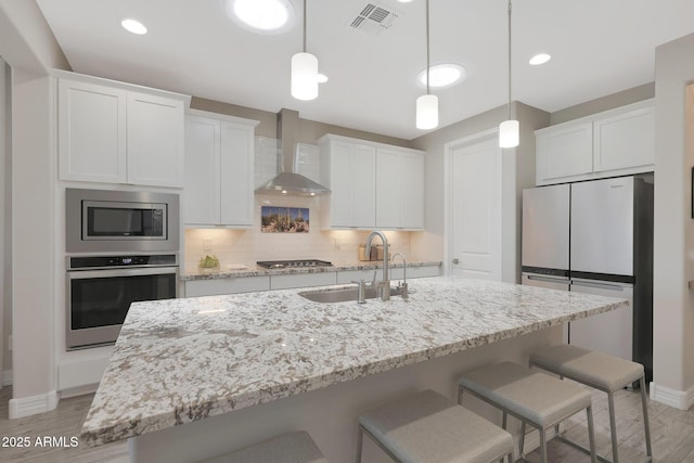 18746 W Rancho Dr, Litchfield Park, AZ 85340 - kitchen featuring a sink, visible vents, stainless steel appliances, baseboards, and wall chimney exhaust hood