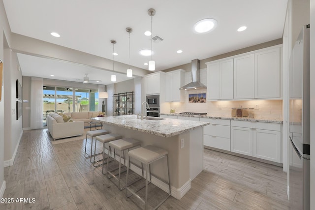 18746 W Rancho Dr, Litchfield Park, AZ 85340 - kitchen with decorative backsplash, stainless steel appliances, white cabinets, wall chimney exhaust hood, and open floor plan