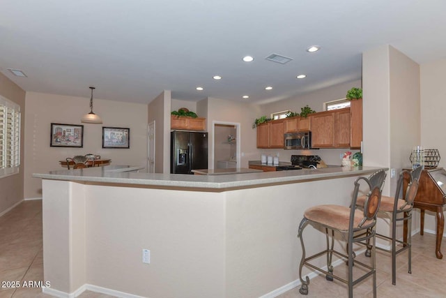 kitchen with hanging light fixtures, a kitchen breakfast bar, black appliances, light tile patterned flooring, and kitchen peninsula