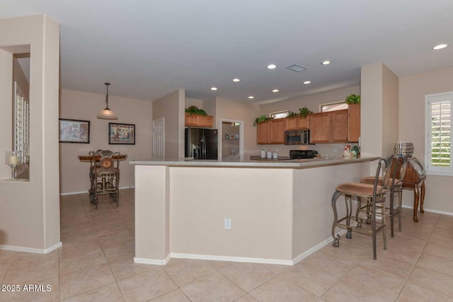 kitchen featuring light tile patterned flooring, a kitchen bar, black fridge with ice dispenser, kitchen peninsula, and pendant lighting