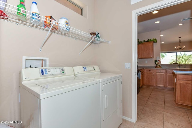 laundry room featuring an inviting chandelier, sink, light tile patterned floors, and washer and clothes dryer