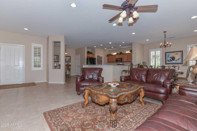 living room with light tile patterned flooring and ceiling fan with notable chandelier