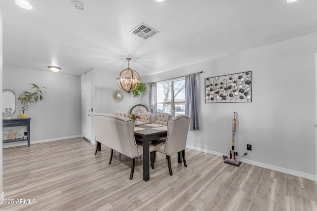 dining area with light wood-type flooring and a notable chandelier