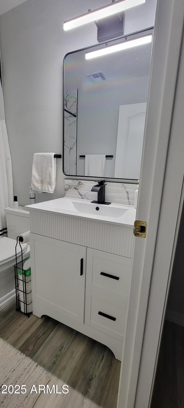 bathroom featuring toilet, vanity, and hardwood / wood-style floors