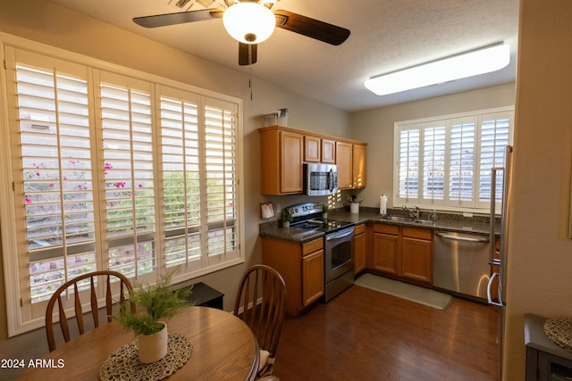 kitchen featuring sink, stainless steel appliances, dark hardwood / wood-style floors, dark stone counters, and a textured ceiling