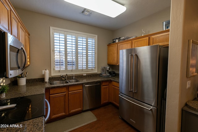 kitchen featuring dark hardwood / wood-style flooring, sink, appliances with stainless steel finishes, and dark stone counters