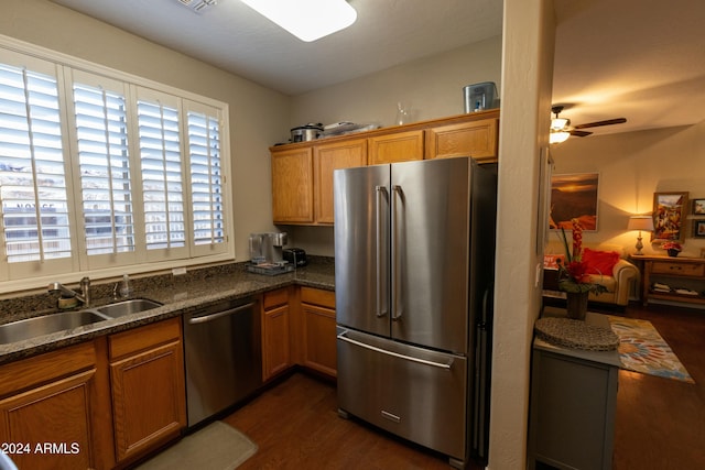 kitchen with ceiling fan, sink, dark hardwood / wood-style flooring, dark stone countertops, and appliances with stainless steel finishes