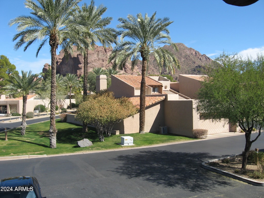 view of front facade with central AC, a front lawn, and a mountain view