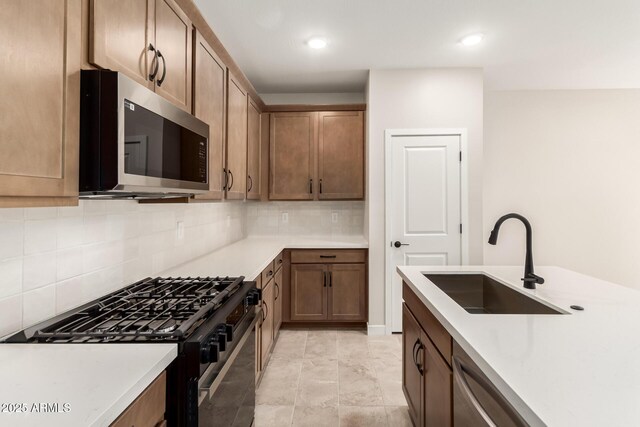 5641 N 205th Ln, Buckeye, AZ 85396 - kitchen with stainless steel microwave, black range with gas cooktop, a sink, tasteful backsplash, and light countertops