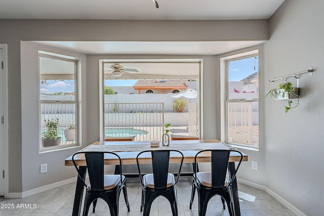 dining space with ceiling fan, baseboards, and light tile patterned flooring