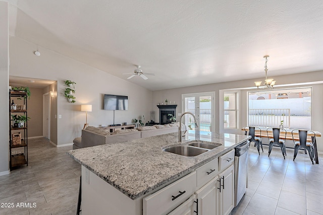 kitchen featuring a sink, a kitchen island with sink, dishwasher, lofted ceiling, and white cabinetry