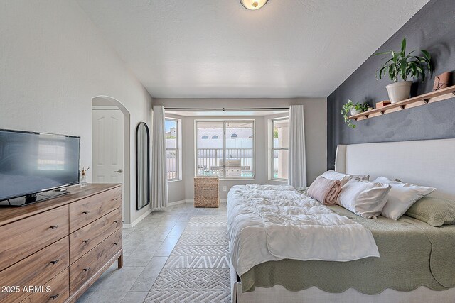 bedroom with arched walkways and light tile patterned floors