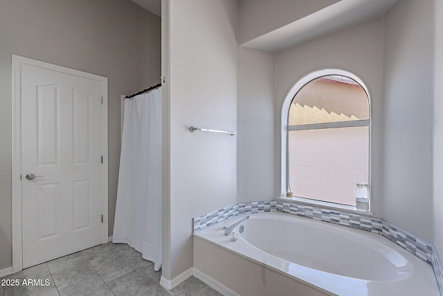 bathroom featuring a garden tub, tile patterned floors, and baseboards