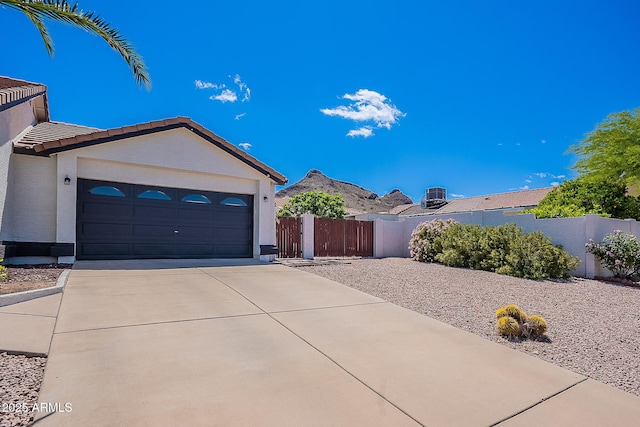 exterior space with a tile roof, concrete driveway, fence, a garage, and stucco siding