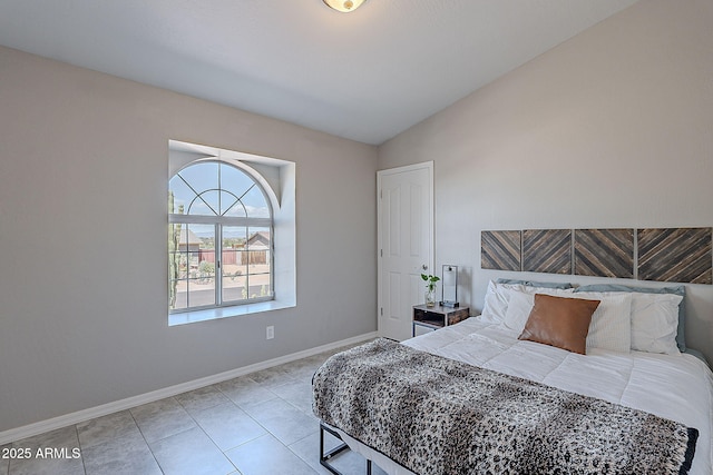 tiled bedroom featuring lofted ceiling and baseboards