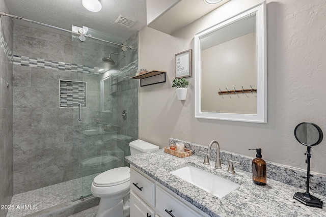 bathroom featuring a shower stall, visible vents, toilet, and vanity