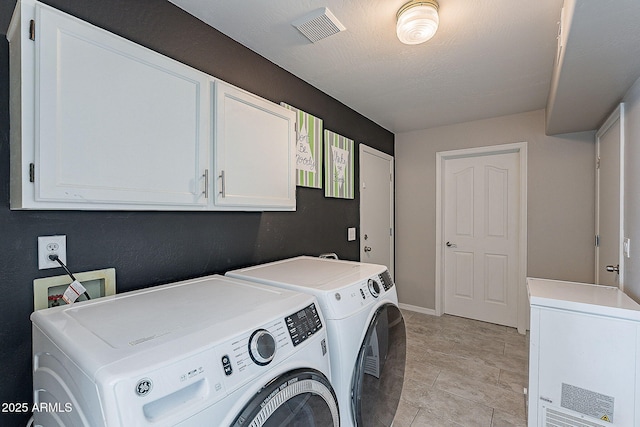 clothes washing area with baseboards, visible vents, independent washer and dryer, and cabinet space