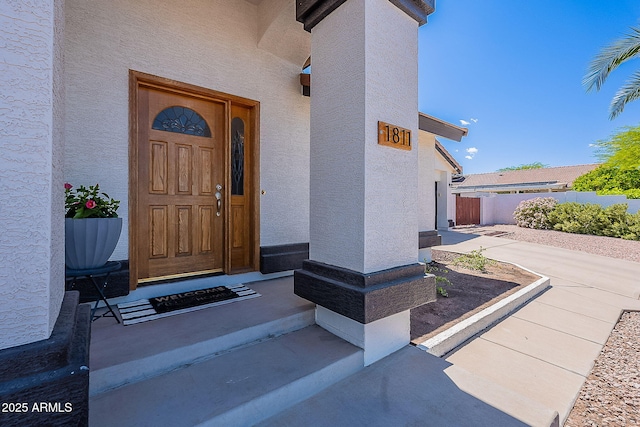 property entrance with stucco siding and fence