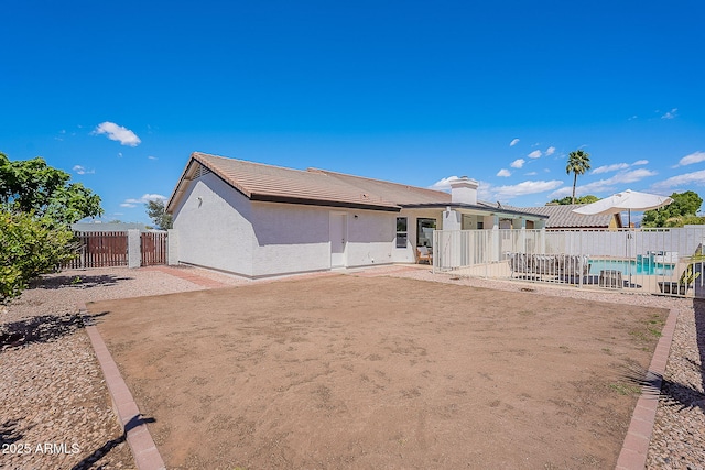 back of property with a fenced in pool, fence, stucco siding, a tile roof, and a patio