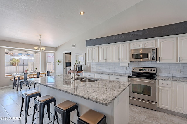 kitchen with a sink, an inviting chandelier, lofted ceiling, decorative backsplash, and appliances with stainless steel finishes