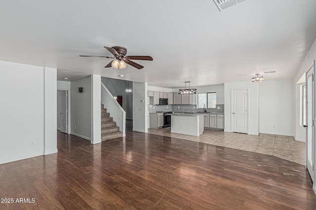 23637 N Desert Dr, Florence, AZ 85132 - unfurnished living room with a sink, light wood-style floors, stairway, ceiling fan, and a chandelier