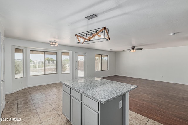 23637 N Desert Dr, Florence, AZ 85132 - kitchen featuring gray cabinets, ceiling fan, light tile patterned flooring, open floor plan, and a kitchen island