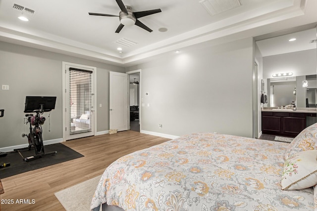 3331 N Acacia Way, Buckeye, AZ 85396 - bedroom featuring a tray ceiling, light wood-type flooring, recessed lighting, baseboards, and ensuite bath