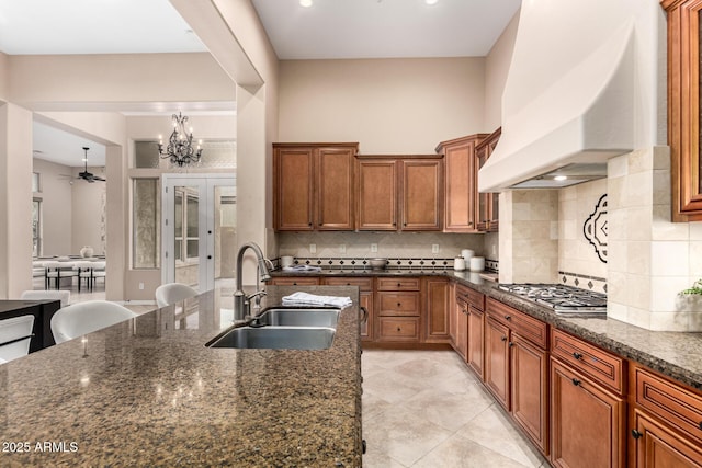 28247 N 128th Dr, Peoria, AZ 85383 - kitchen with brown cabinets, stainless steel gas cooktop, custom range hood, decorative backsplash, and a sink
