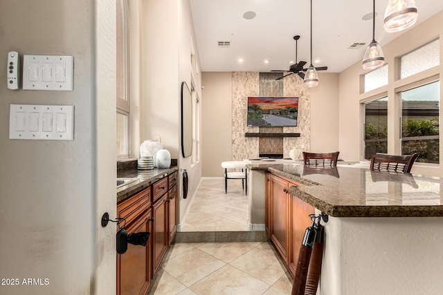 28247 N 128th Dr, Peoria, AZ 85383 - kitchen featuring dark stone counters, brown cabinets, and visible vents
