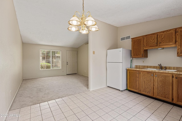 6711 W Osborn Rd Unit 82, Phoenix, AZ 85033 - kitchen with freestanding refrigerator, lofted ceiling, a chandelier, light colored carpet, and brown cabinetry