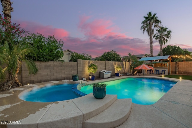 5628 N Rattler Way, Litchfield Park, AZ 85340 - pool at dusk with a patio area, a fenced backyard, and a pool with connected hot tub