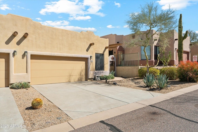 adobe home featuring stucco siding, an attached garage, and driveway